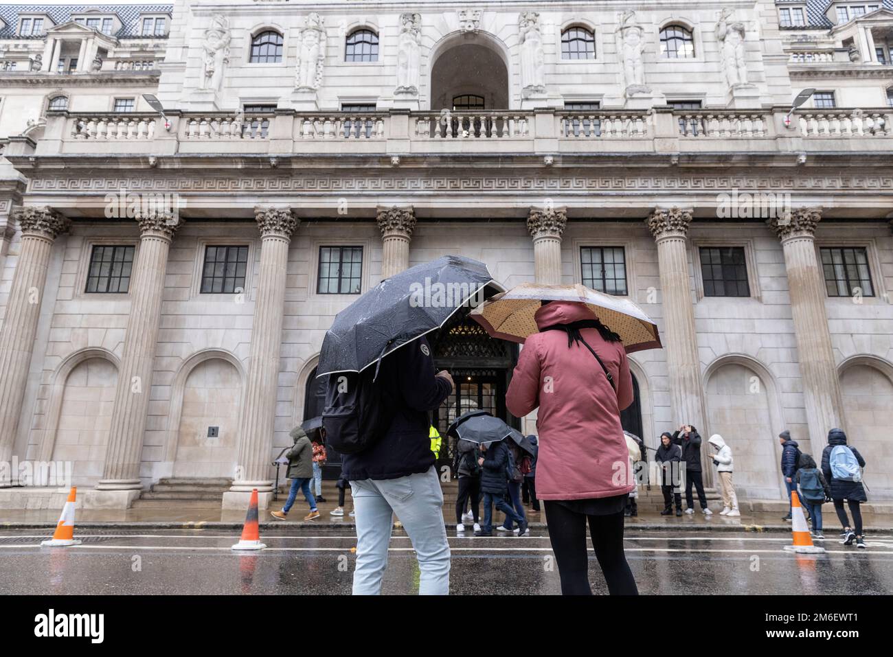 La gente copre dalla pioggia invernale sotto i loro ombrelli al di fuori della Bank of England, nel Square Mile, City of London, UK Foto Stock