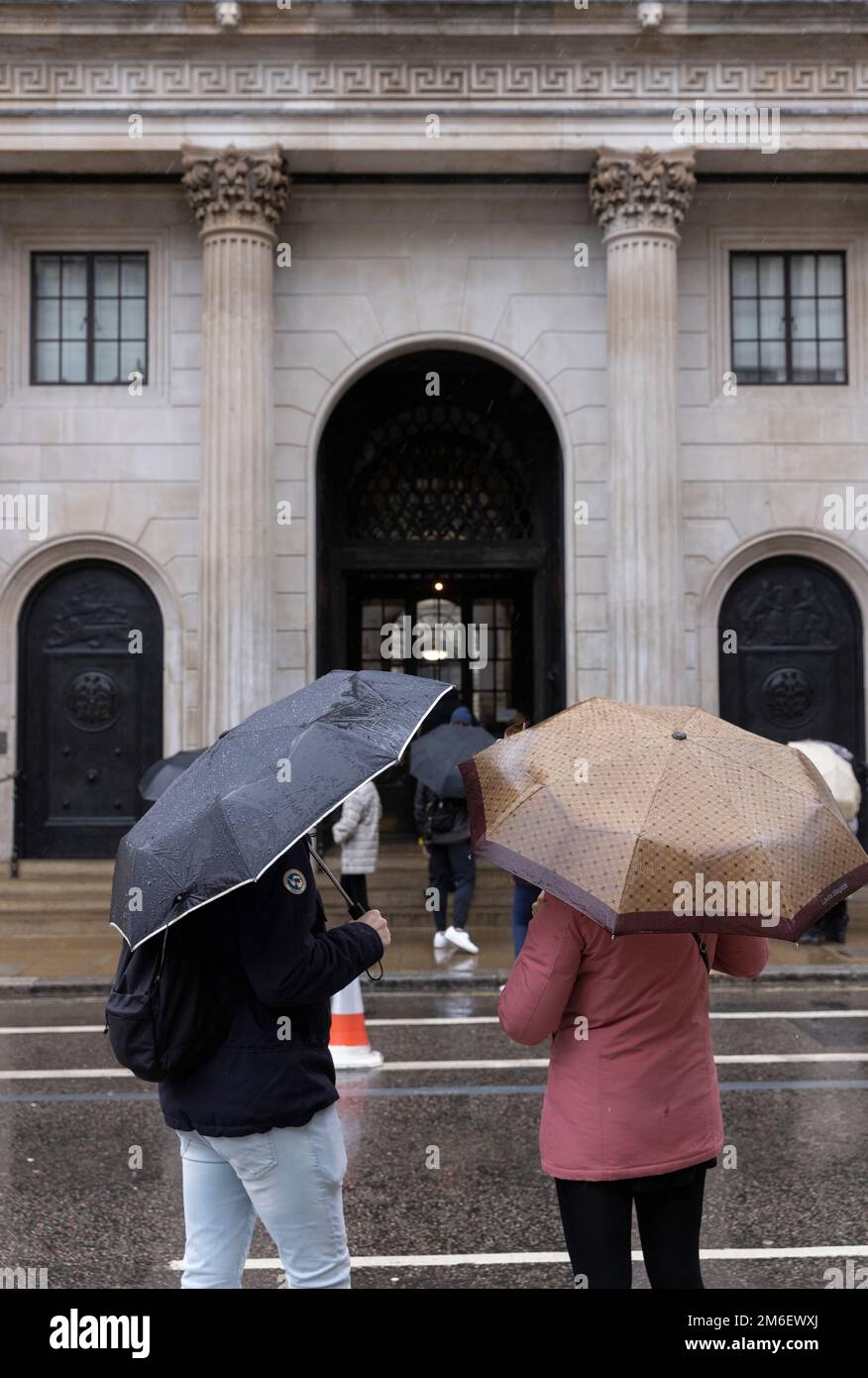 La gente copre dalla pioggia invernale sotto i loro ombrelli al di fuori della Bank of England, nel Square Mile, City of London, UK Foto Stock