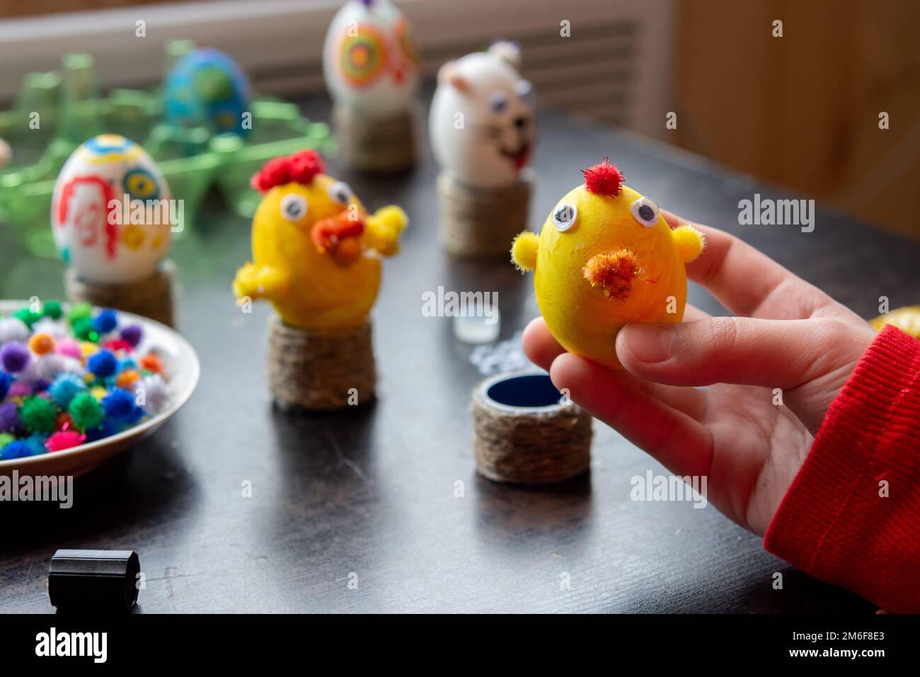 Il bambino ha fatto una figurina di un pollo da un uovo e lo mostra nella cornice, sullo sfondo altre figure Foto Stock