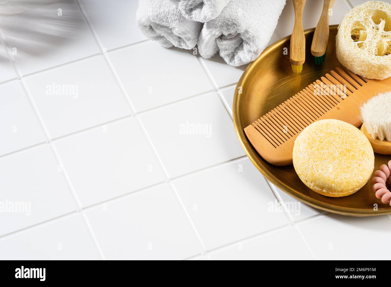 Shampoo bar solido e accessori da bagno su sfondo bianco in ceramica. Senza plastica, senza sprechi, ingredienti a basso contenuto d'acqua. Cura sostenibile dei capelli Foto Stock