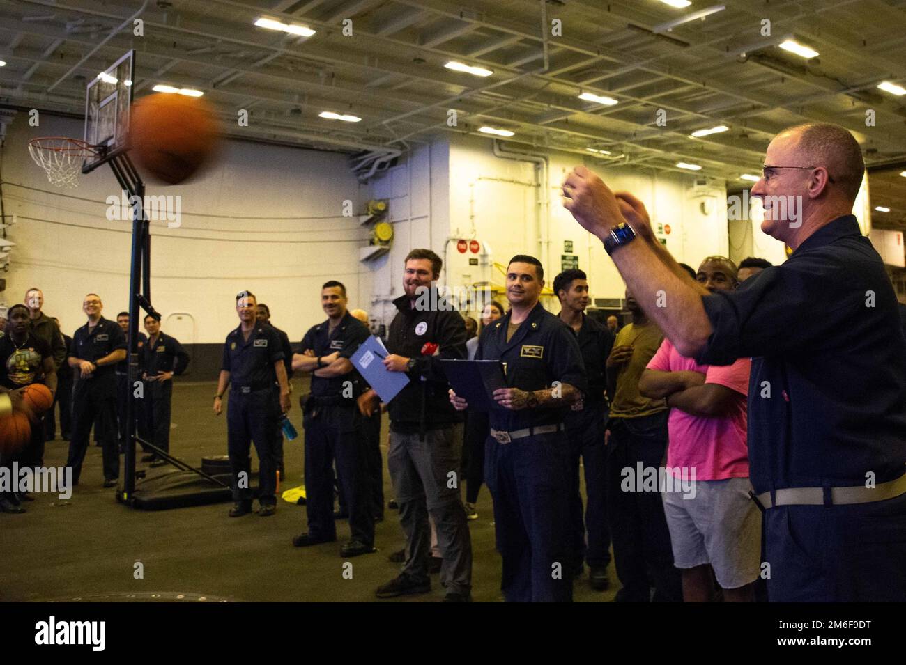 220427-N-EE352-1103 OCEANO PACIFICO (27 aprile 2022) il capitano P. Scott Miller, comandante della portaerei di classe Nimitz USS Carl Vinson (CVN 70), partecipa a un concorso di tiro al basket a tre punti, nella baia dell'hangar, aprile 27. Vinson sta attualmente conducendo operazioni marittime di routine nell'Oceano Pacifico. Foto Stock