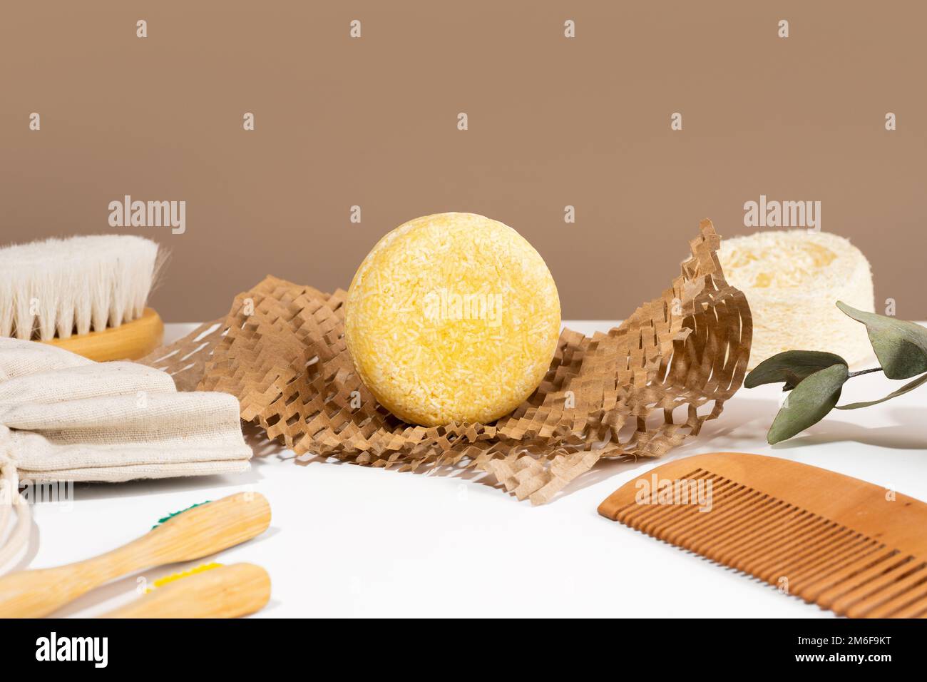 Barra di shampoo solida ecologica su carta Honeycomb e materiali naturali accessori per il bagno giacenti su sfondo bianco e marrone. Senza plastica, ZE Foto Stock