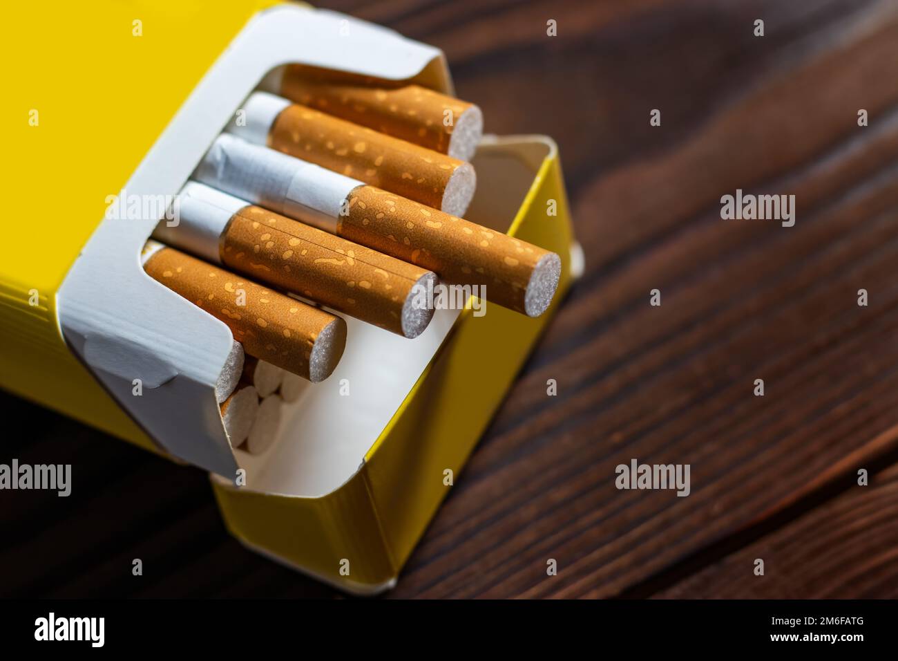 Sigarette in una confezione. Filtro giallo. Danni alla salute. Cattiva abitudine. Una confezione di sigarette sul tavolo. aprire il pacchetto di sigarette. Foto Stock