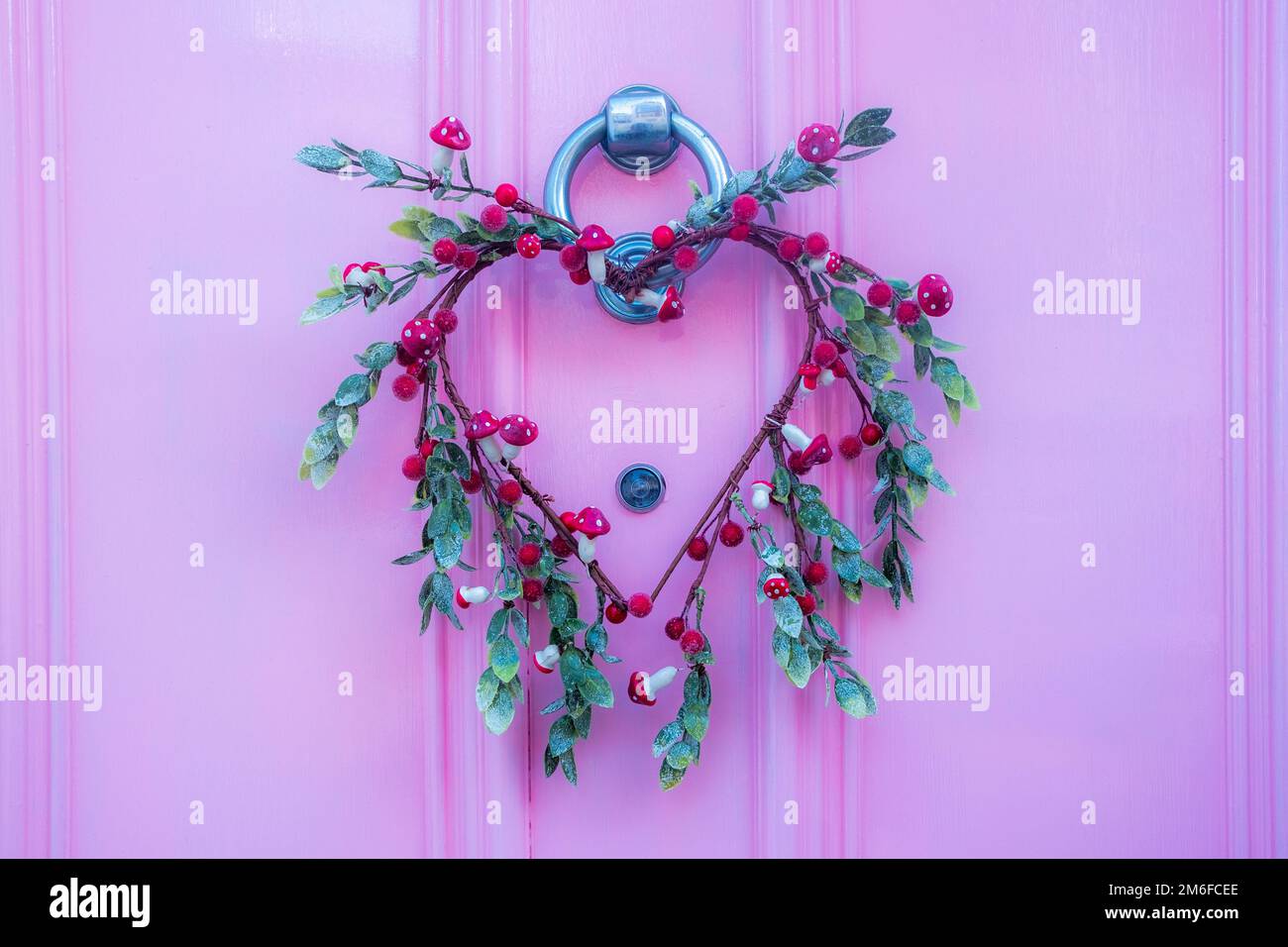 Decorazione a forma di cuore della porta wreath su porta rosa Foto Stock