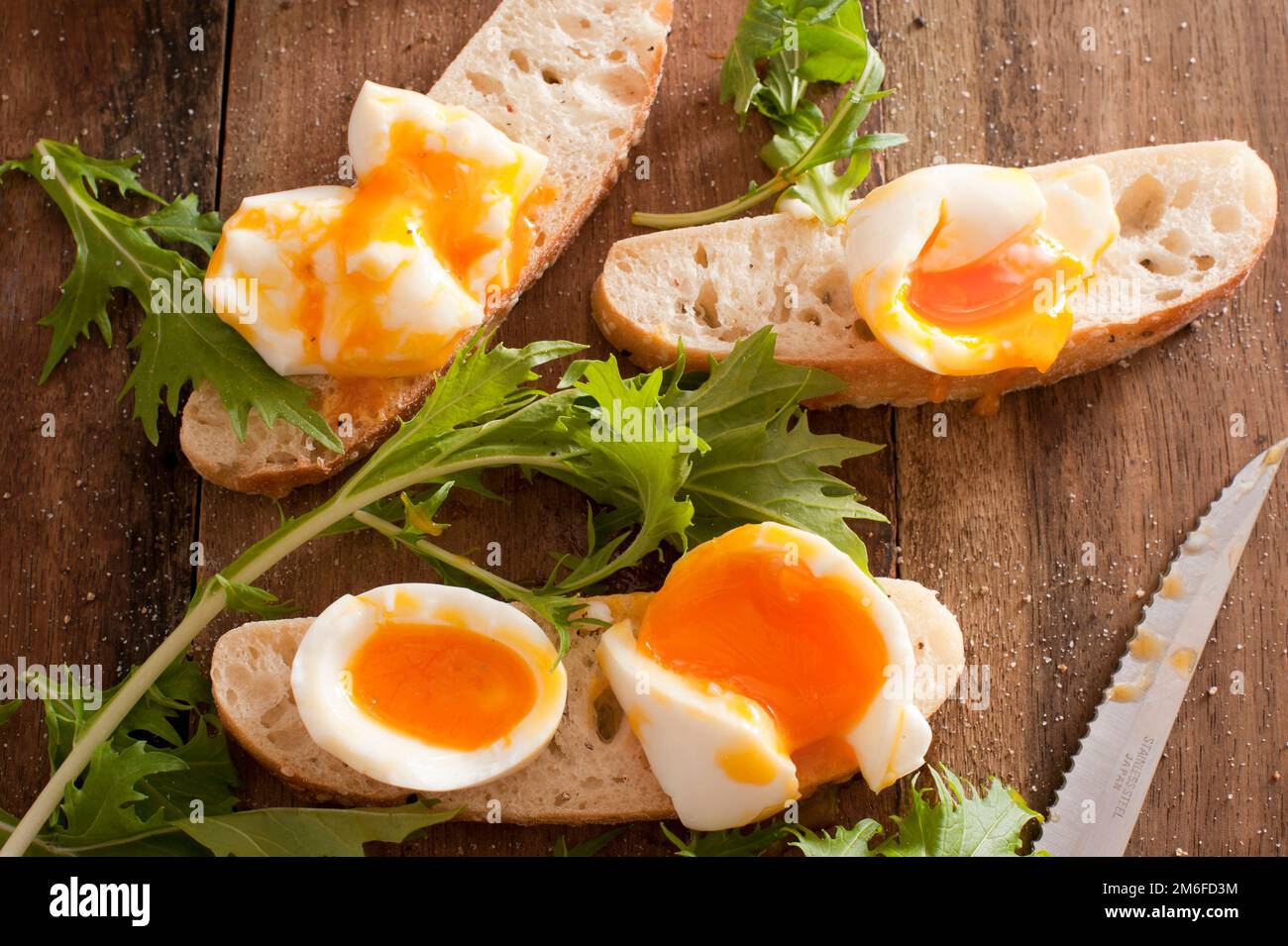Uova sode rotte su baguette Foto Stock