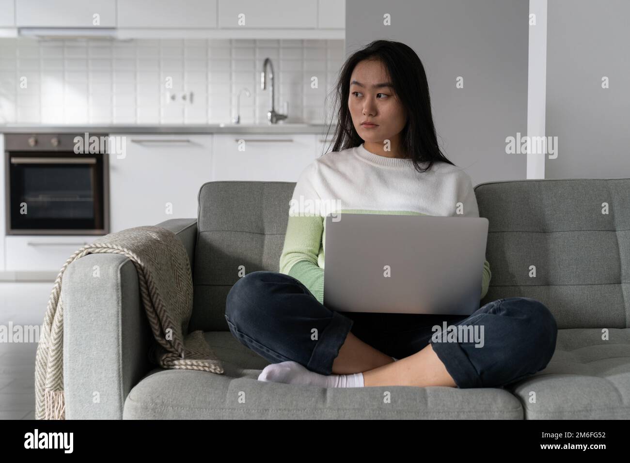 Giovane donna asiatica premurosa che tiene il laptop in giro in attesa di messaggi e-mail importanti Foto Stock