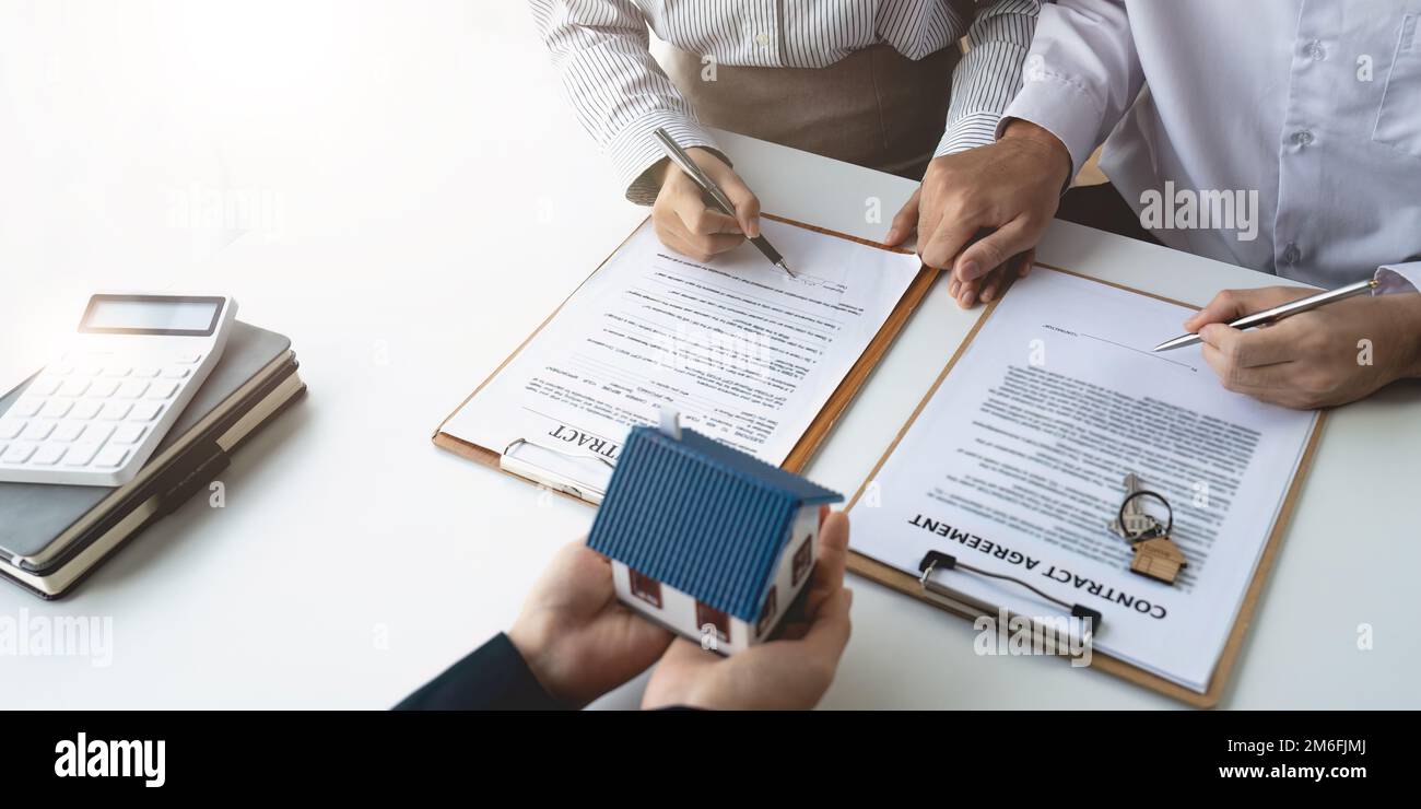 Agente immobiliare con coppia che chiude un affare e firma un contratto. Foto Stock