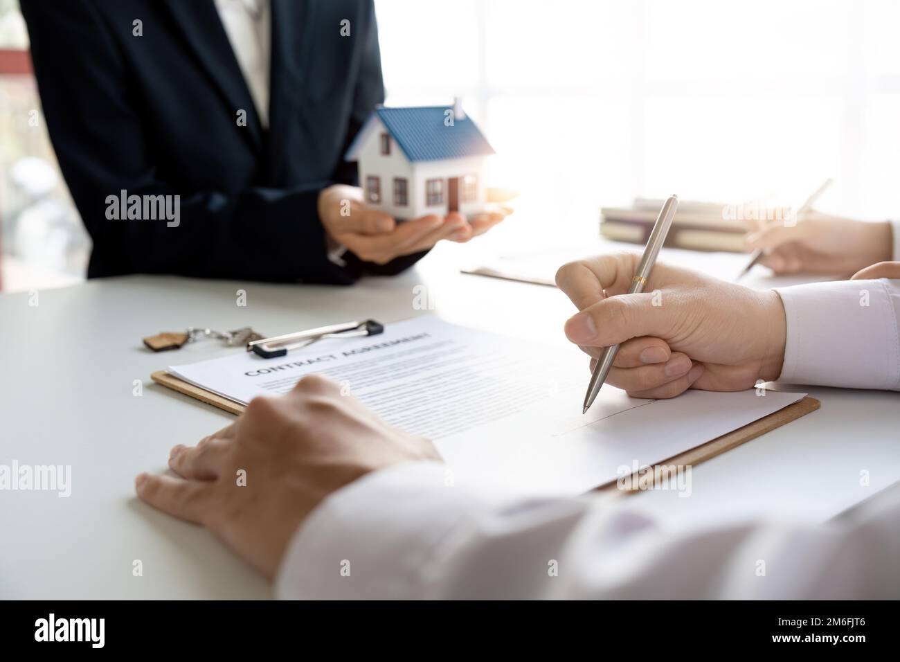 Agente immobiliare con coppia che chiude un affare e firma un contratto. Foto Stock