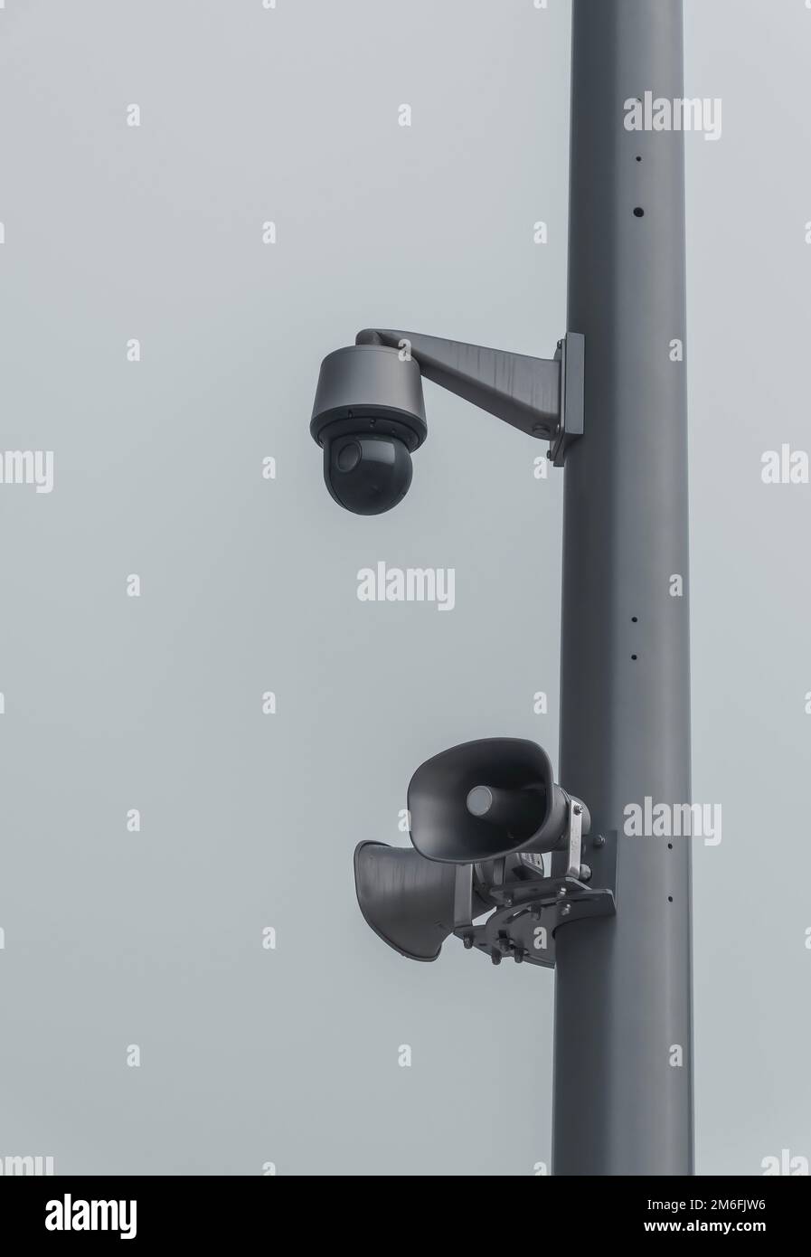 Un primo piano di una telecamera di sicurezza e di altoparlanti su un palo in una giornata di nebbia Foto Stock