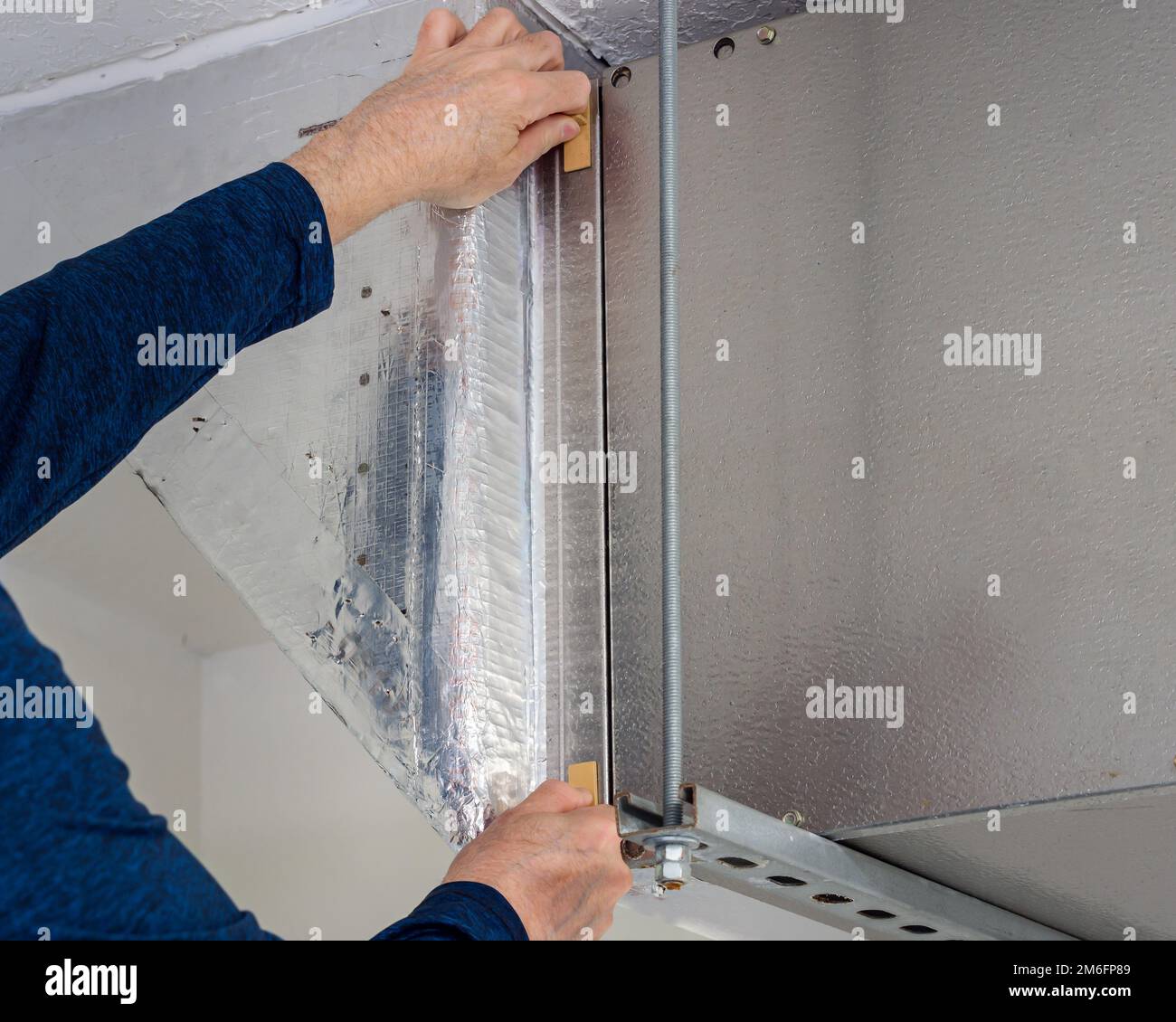 Tecnico dell'assistenza HVAC che sostituisce il filtro dell'aria interna sporco nell'impianto di riscaldamento e climatizzazione residenziale. Manutenzione del sistema di ventilazione dei condotti d'aria domestici Foto Stock