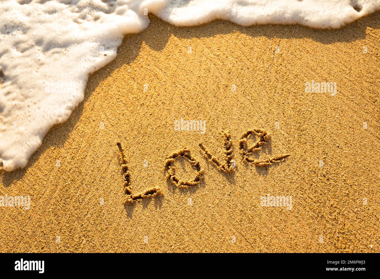 La parola AMORE scritto nella sabbia sulla spiaggia Foto Stock
