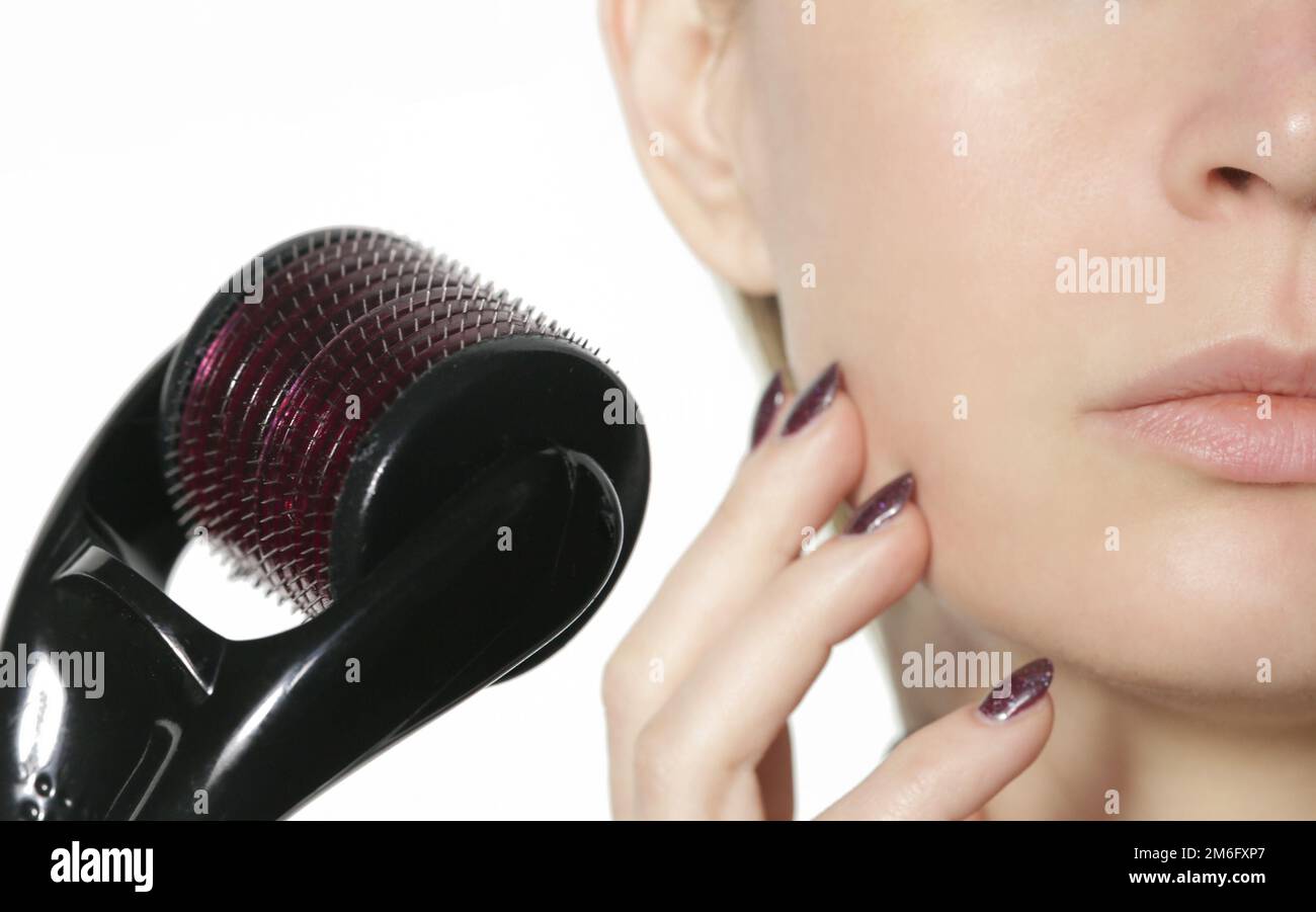 Massaggio facciale con microneedle dermaroller per il trattamento di cicatrici, rughe e ringiovanimento facciale. Cura della pelle semplice ed economica nel paese. Foto Stock