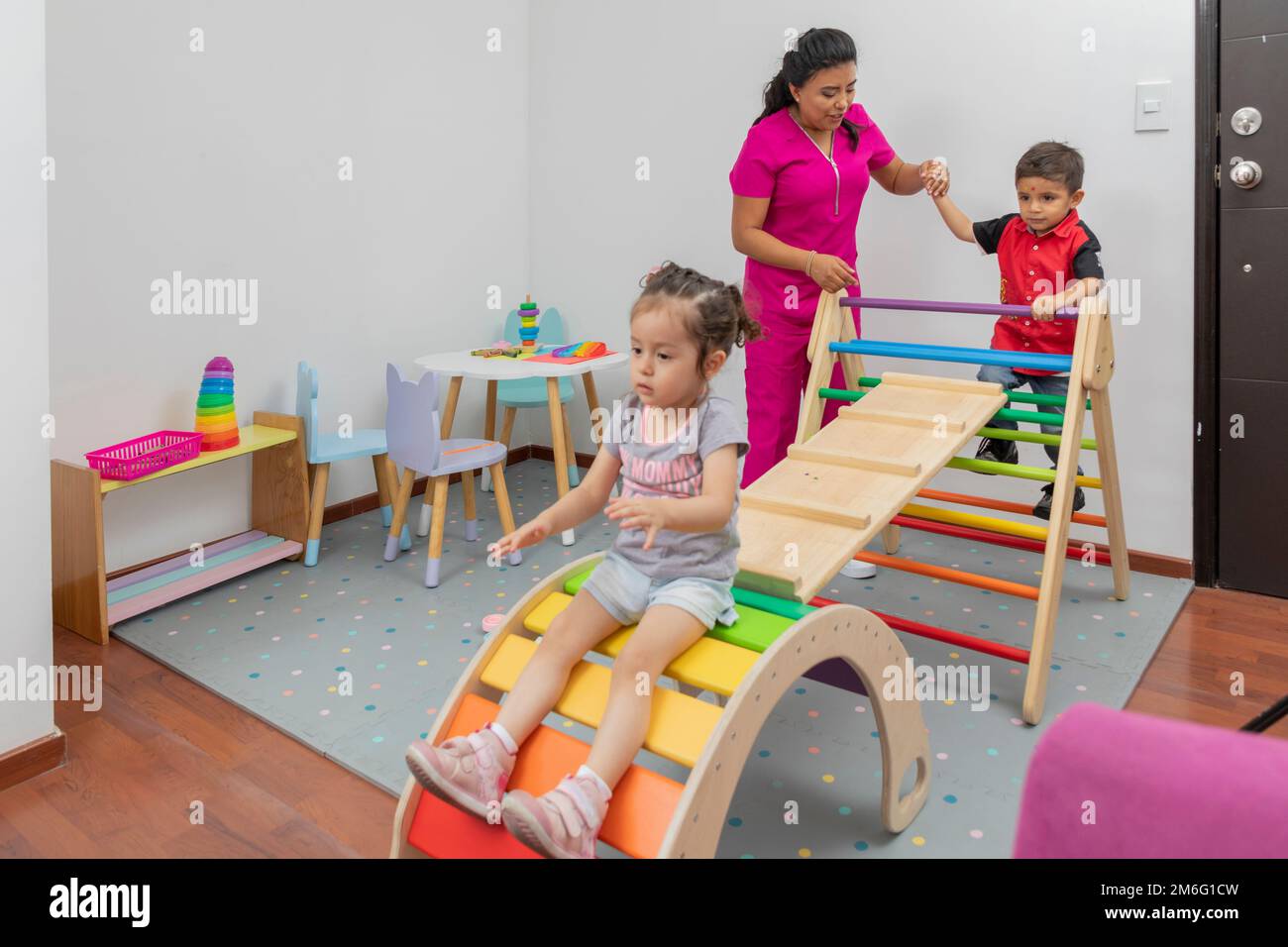 Medico pediatrico che gioca con un ragazzo e una ragazza, nella sala giochi del suo ufficio. Foto Stock