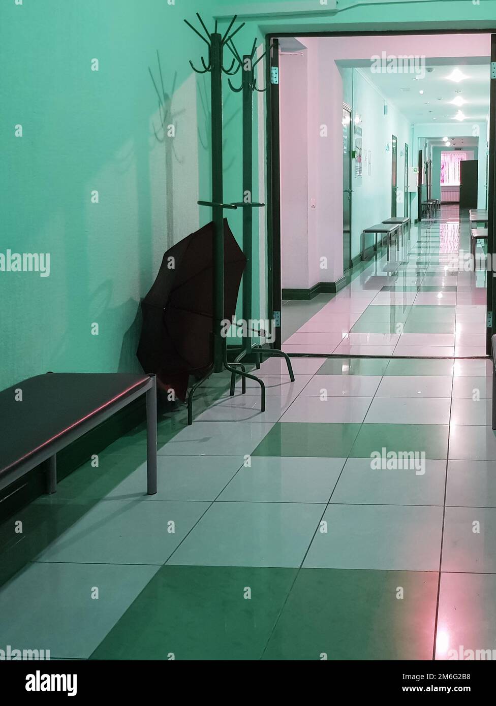 Appendiabiti in legno con ombrello aperto in una stanza vuota del corridoio di una clinica medica, verticale Foto Stock