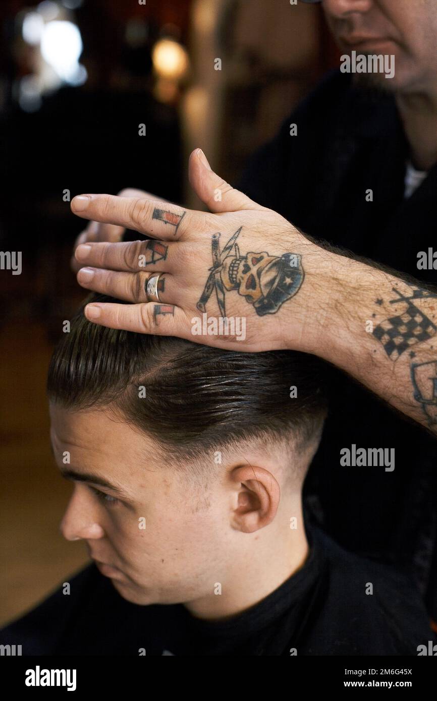 Barber sta tagliando i capelli del giovane uomo. Foto Stock