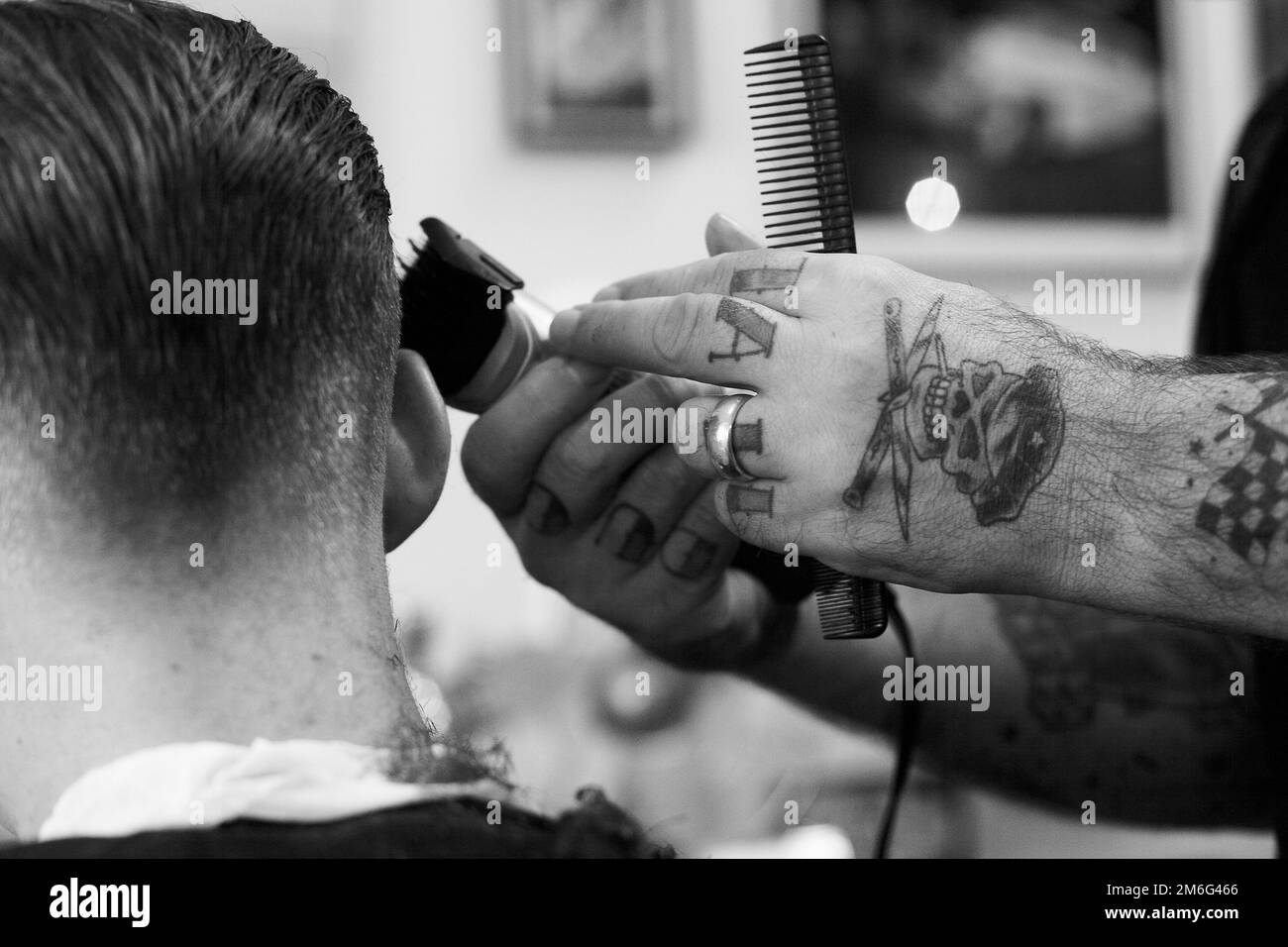 Barber sta tagliando i capelli del giovane uomo. Vista posteriore dell'uomo che ottiene la rifinitura dei capelli corti al barbiere con una macchina del regolacapelli. Foto Stock