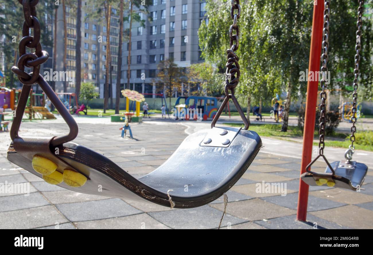 Primo piano vuoto baby swing nel parco. Nuova rotazione della catena. Set di catene nere oscillanti in un moderno parco giochi. Concentratevi sul swing in Foto Stock