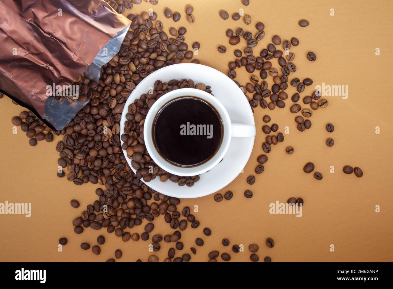 Tazza bianca di caffè americano nero senza latte con un mazzetto di chicchi di caffè tostati sparsi dalla confezione di carta. Caffè bac Foto Stock