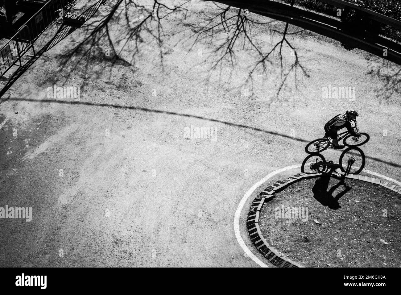 Un ciclista che corre lungo Tibidabo a Barcellona in una giornata invernale di sole. Foto in bianco e nero con molte ombre dure. Foto Stock