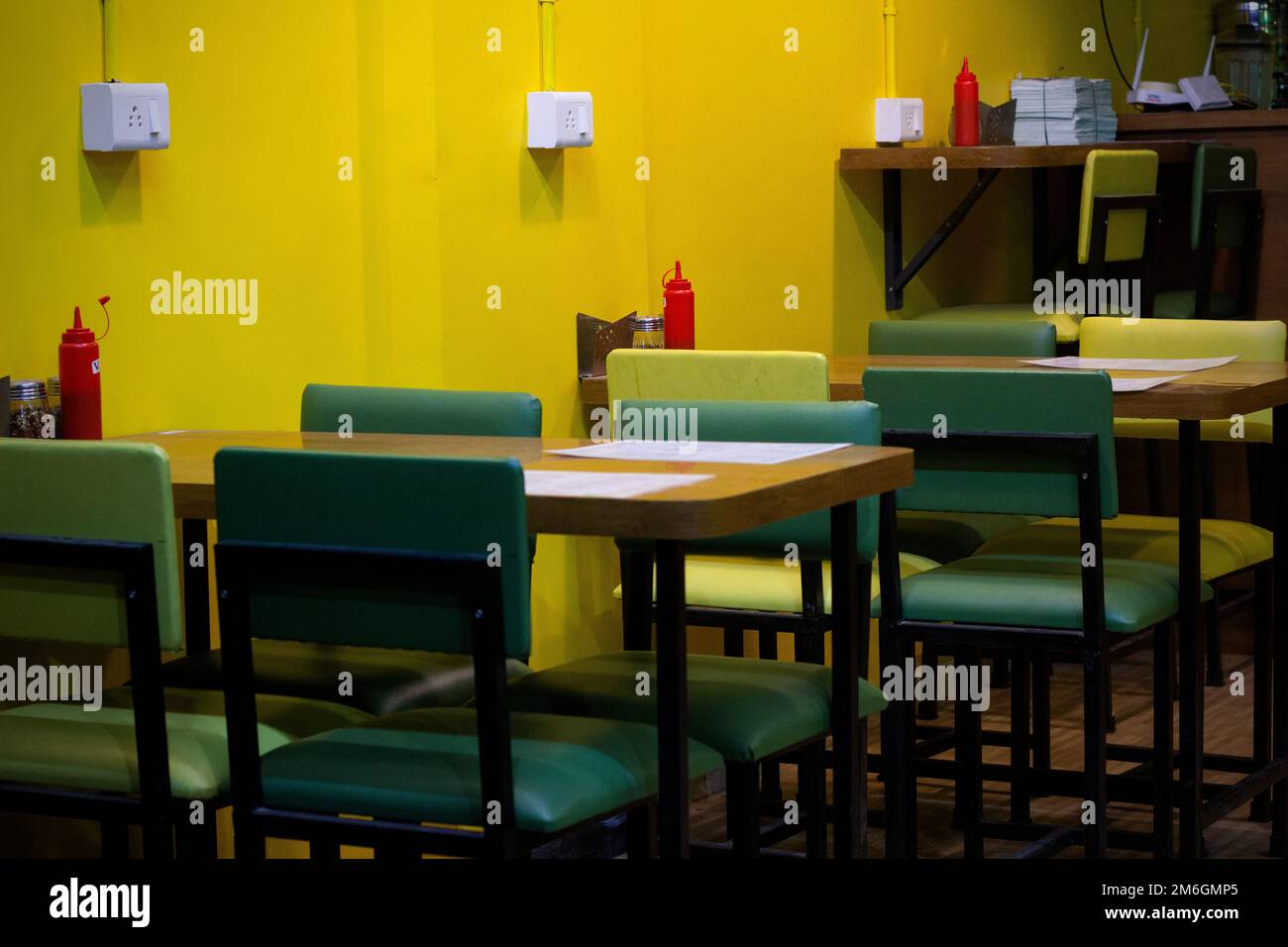 Tavoli e sedie sono disposti in un buon negozio di cibo interno fresco e luminoso con un tema di colore scuro. Foto Stock