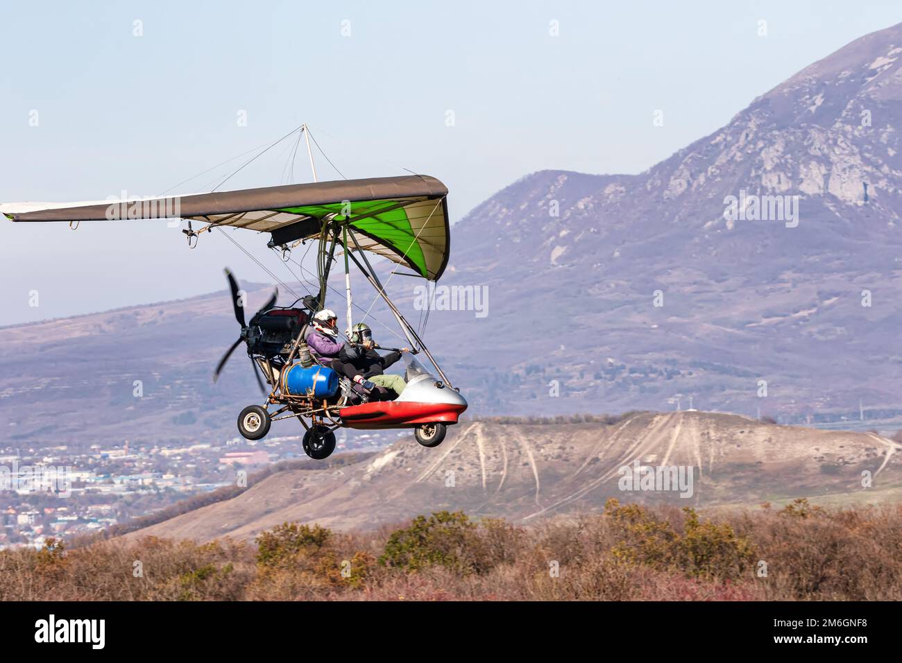 Volo su un parapendio motorizzato in terreno montano Foto Stock