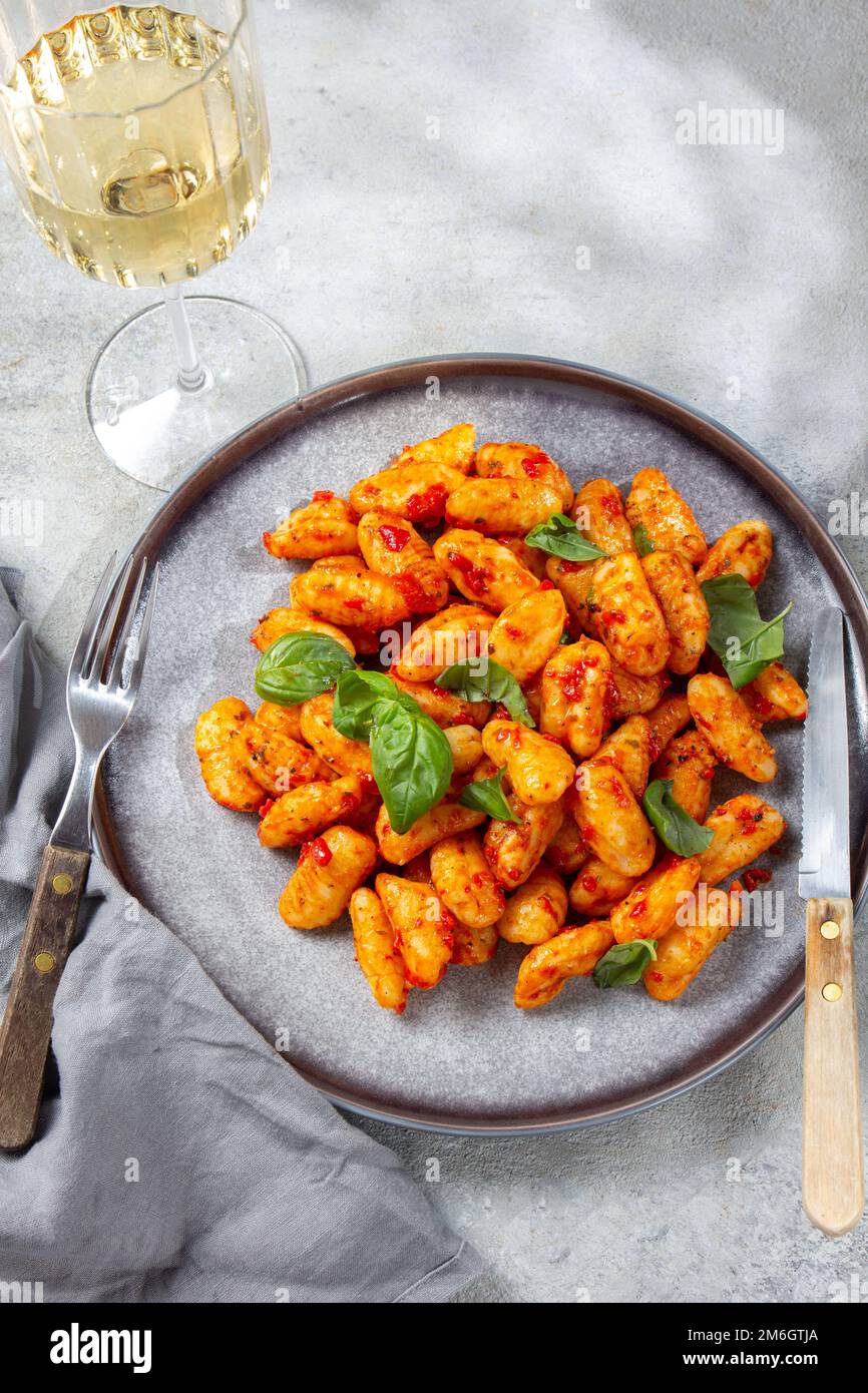 Gnocchi di patate tradizionali italiane con salsa di pomodoro e basilico fresco su piatto grigio, marmorizzato sul dorso Foto Stock