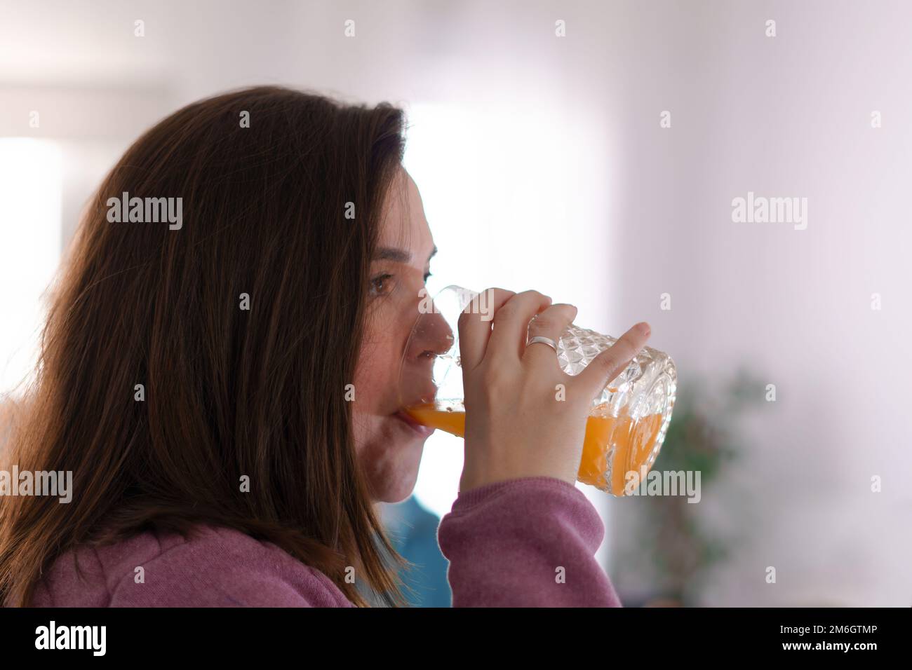 ragazza giovane in profilo bere succo d'arancia appena spremuto Foto Stock