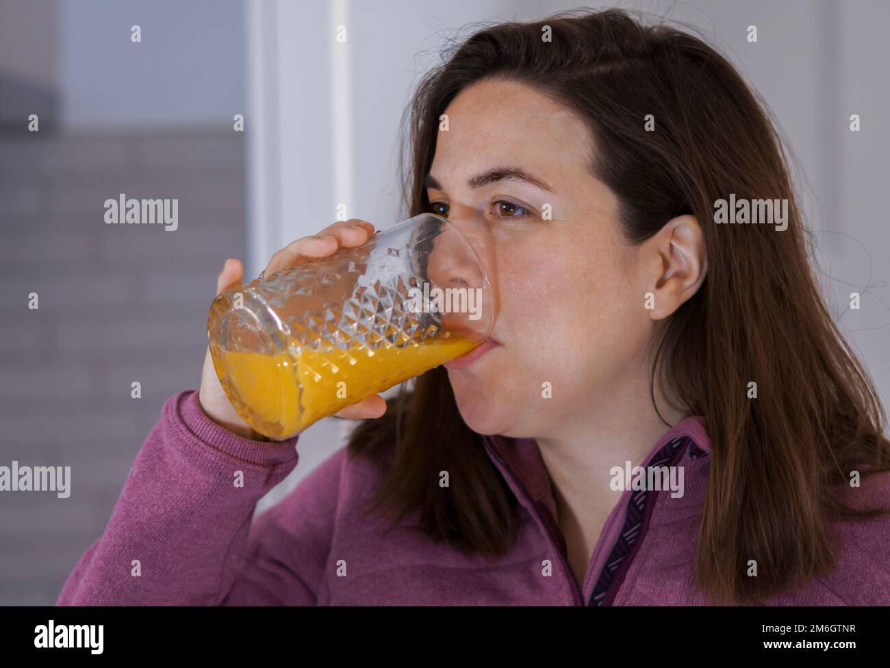 ragazza giovane in profilo bere succo d'arancia appena spremuto Foto Stock