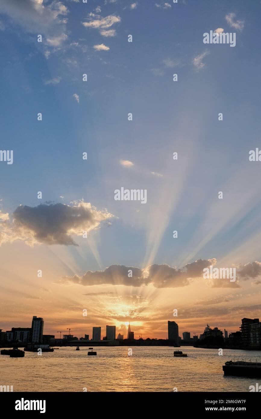 I raggi dorati del sole splendono da dietro lo Shard in lontananza sul tamigi al tramonto a Londra Foto Stock