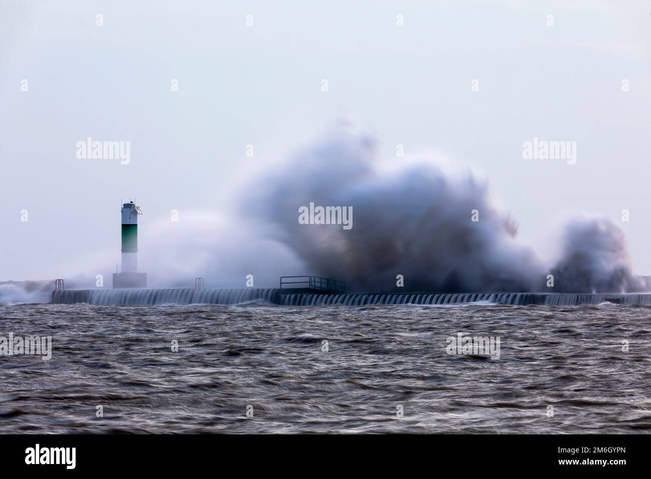 Le onde si schiantano su un molo con un faro sul lago Michigan Foto Stock