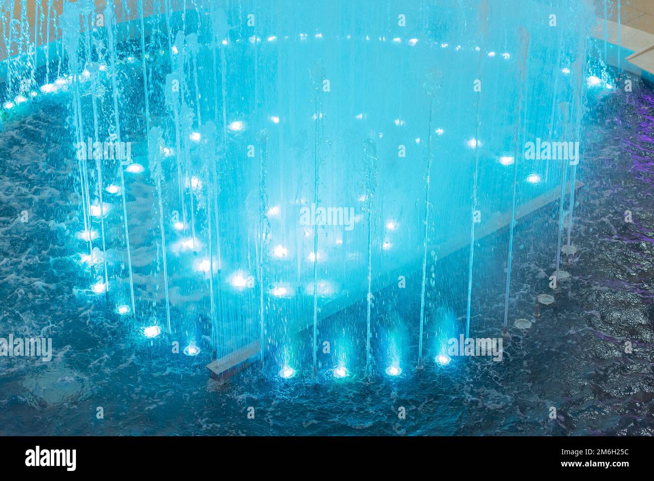 Una fontana con getti illuminati da un'illuminazione blu. Fontana blu canto. Fontana in un centro commerciale Foto Stock