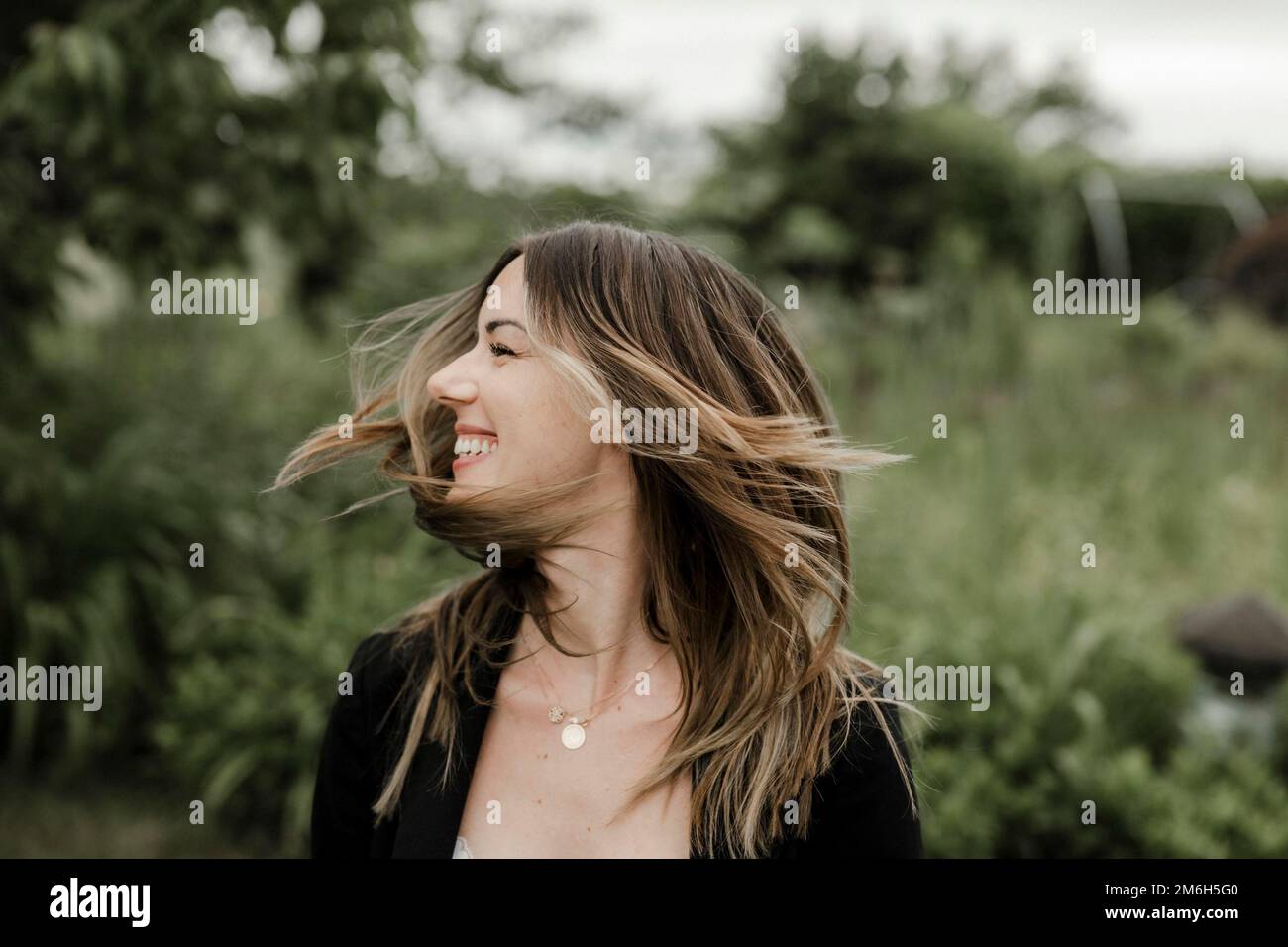 Giovane donna ridente in ritratto, 25, con capelli volanti Foto Stock