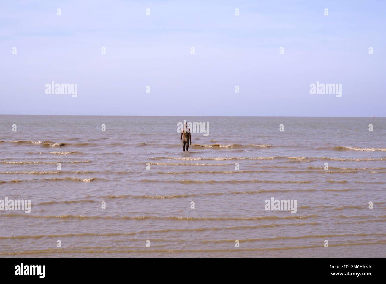 La marea si scontra con la scultura di Anthony Gormley, un altro luogo su Crosby Beach Foto Stock