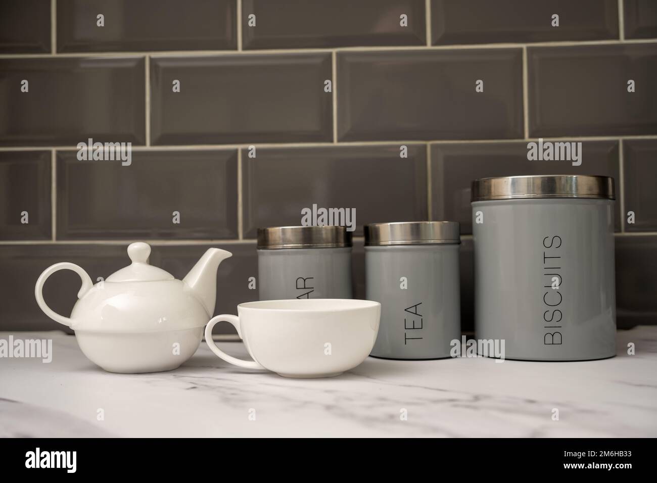 tisana e tazza di porcelin porcellana bianca adagiato su un piano di lavoro in marmo con barattoli di zucchero e biscotto Foto Stock