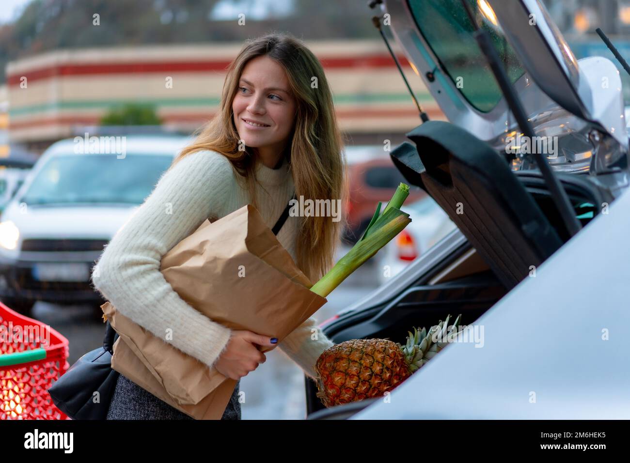 Donna con l'acquisto dal supermercato nel parcheggio, cibo vegetariano, raggiungere l'auto Foto Stock