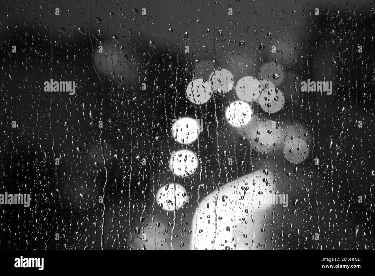 Gocce d'acqua sul vetro della finestra. Luci della città. Bokeh - sfondo astratto dai colori vivaci. Foto Stock