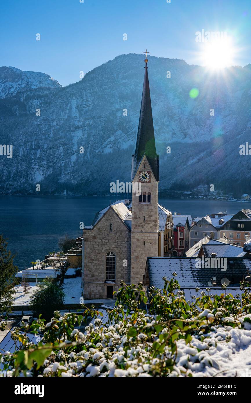 Bella città soleggiata della speciale città Hallstatt in Austria Salzkammergut neve montagne invernali, lago e chiesa . Foto Stock