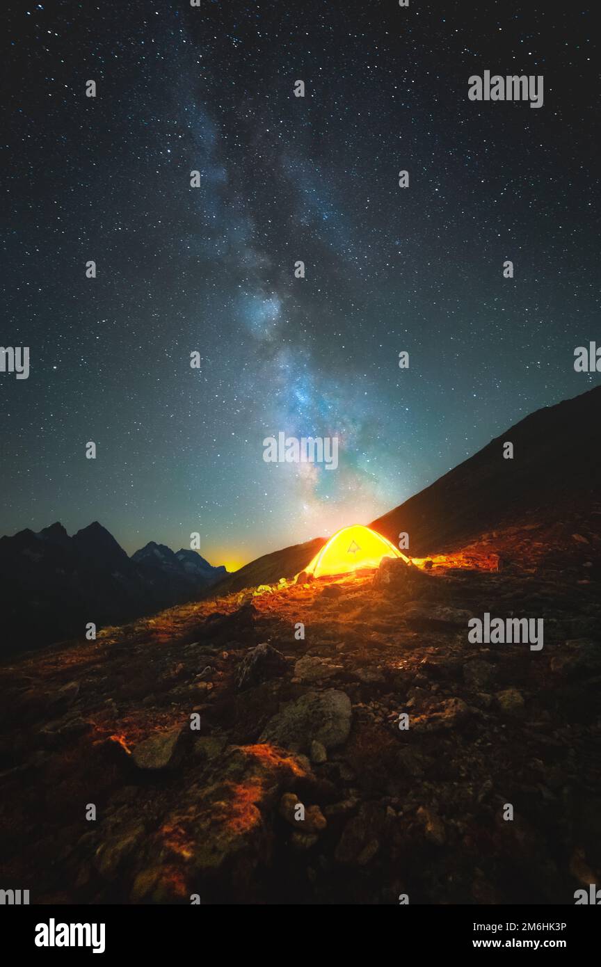 Una foto verticale del cielo stellato alto in montagna. La via lattiginosa saturata indica una luminosa tenda alta sulla montagna Foto Stock