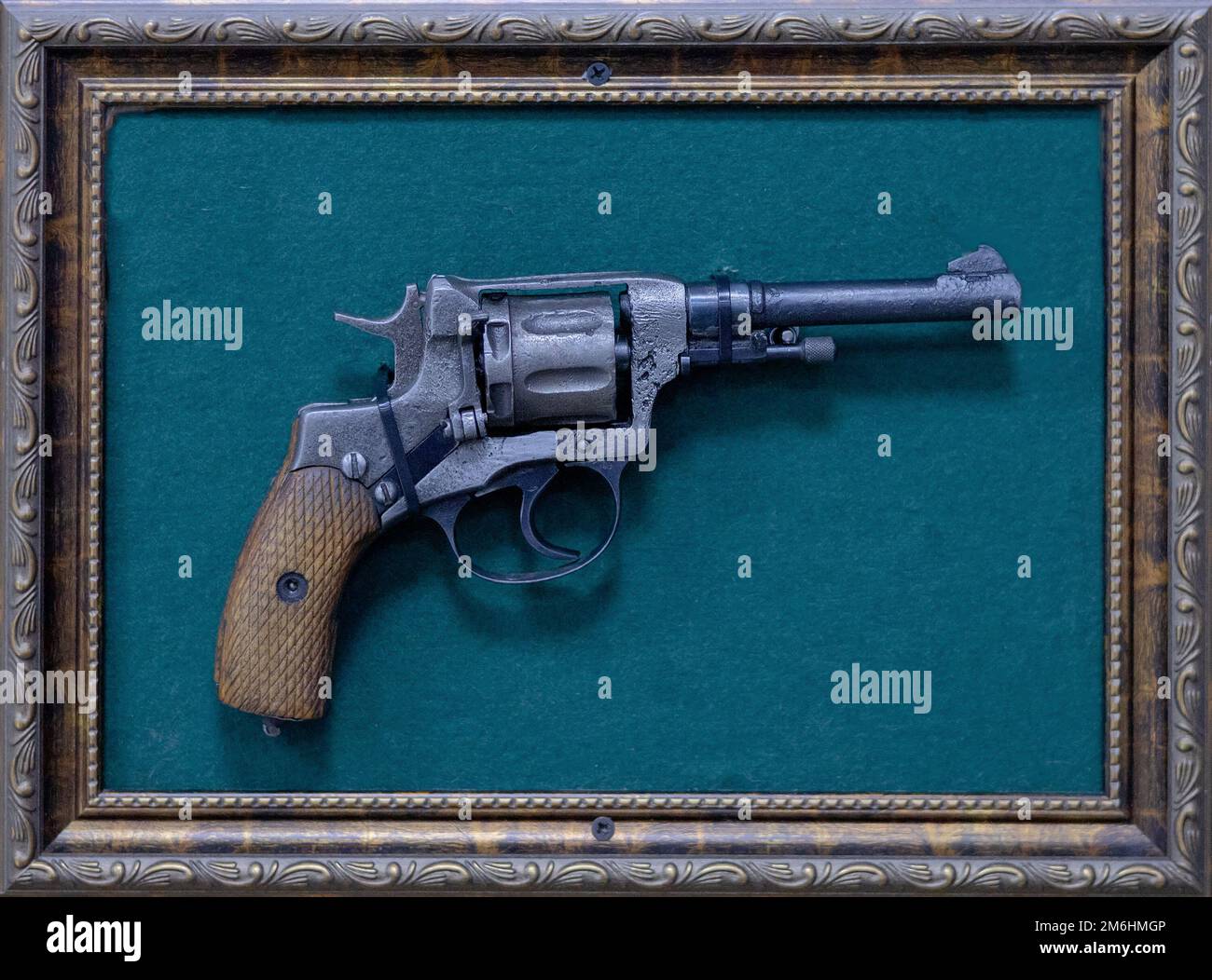 Revolver vecchio in una cornice su uno sfondo turchese. Mostra retrò del museo Foto Stock