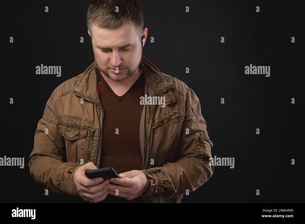 L'uomo caucasico di mezza età usa il telefono mentre si trova in studio. Ritratto di un freelancer che naviga su Internet Foto Stock