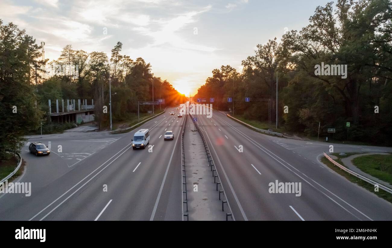Spostamento di auto in autostrada all'ora del tramonto. Traffico autostradale al tramonto con le auto. Traffico intenso sulla superstrada, vista dall'alto della strada. Foto Stock