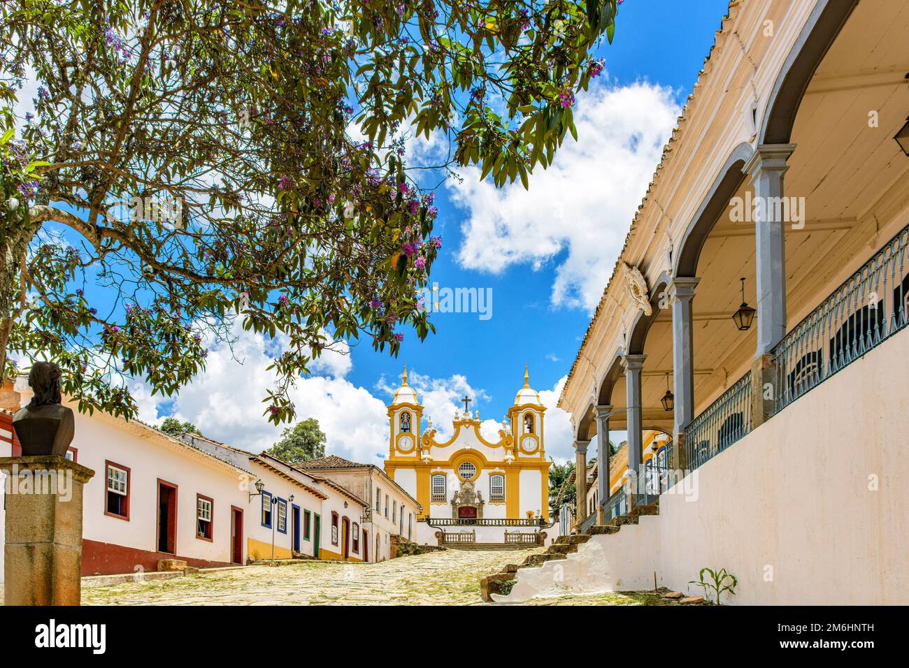 Tranquilla strada storica acciottolata nella città di Tiradentes con le case e la chiesa Foto Stock Tranquilla strada storica acciottolata nella città di Tiradentes con le case e la chiesa Foto Stock