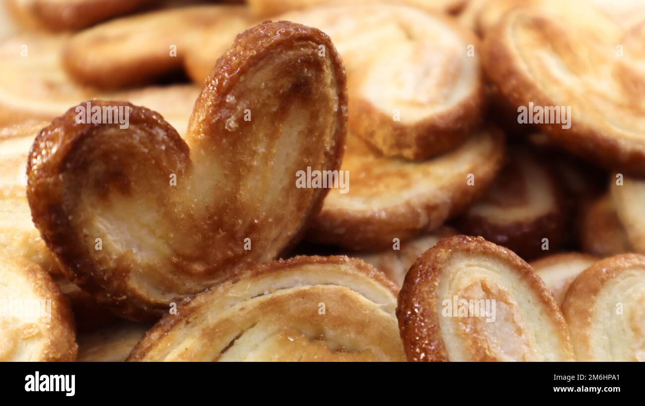 Biscotti freschi di palma con pasta sfoglia a forma di cuore. Pasticceria francese classica. Orecchio di maiale, biscotti all'orecchio di elefante, cuori francesi. Foto Stock