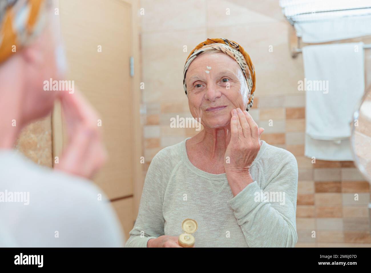 Donna anziana che si prende cura del suo viso Foto Stock