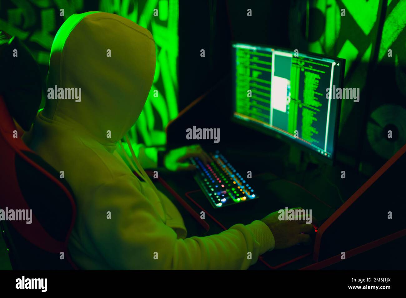 Hacker in Hoodie lavoro hacks codice sito su personal computer con luce verde Foto Stock