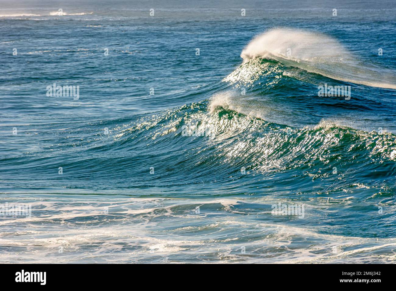 Onda che si interrompe all'alba con riflessi del sole sull'acqua Foto Stock Onda che si interrompe all'alba con riflessi del sole sull'acqua Foto Stock
