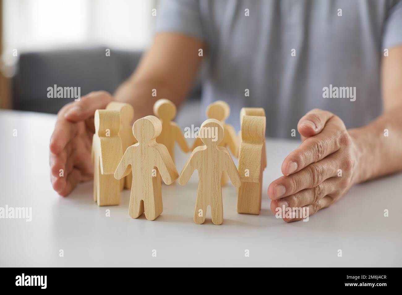 Il piccolo uomo di legno e le mani del reclutatore simboleggiano le attività di team building per le risorse umane Foto Stock