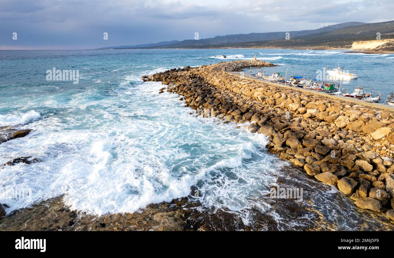 Vista aerea del drone delle barche da pesca ormeggiate al porto a frangiflutti. Onde tempestose in mare Foto Stock