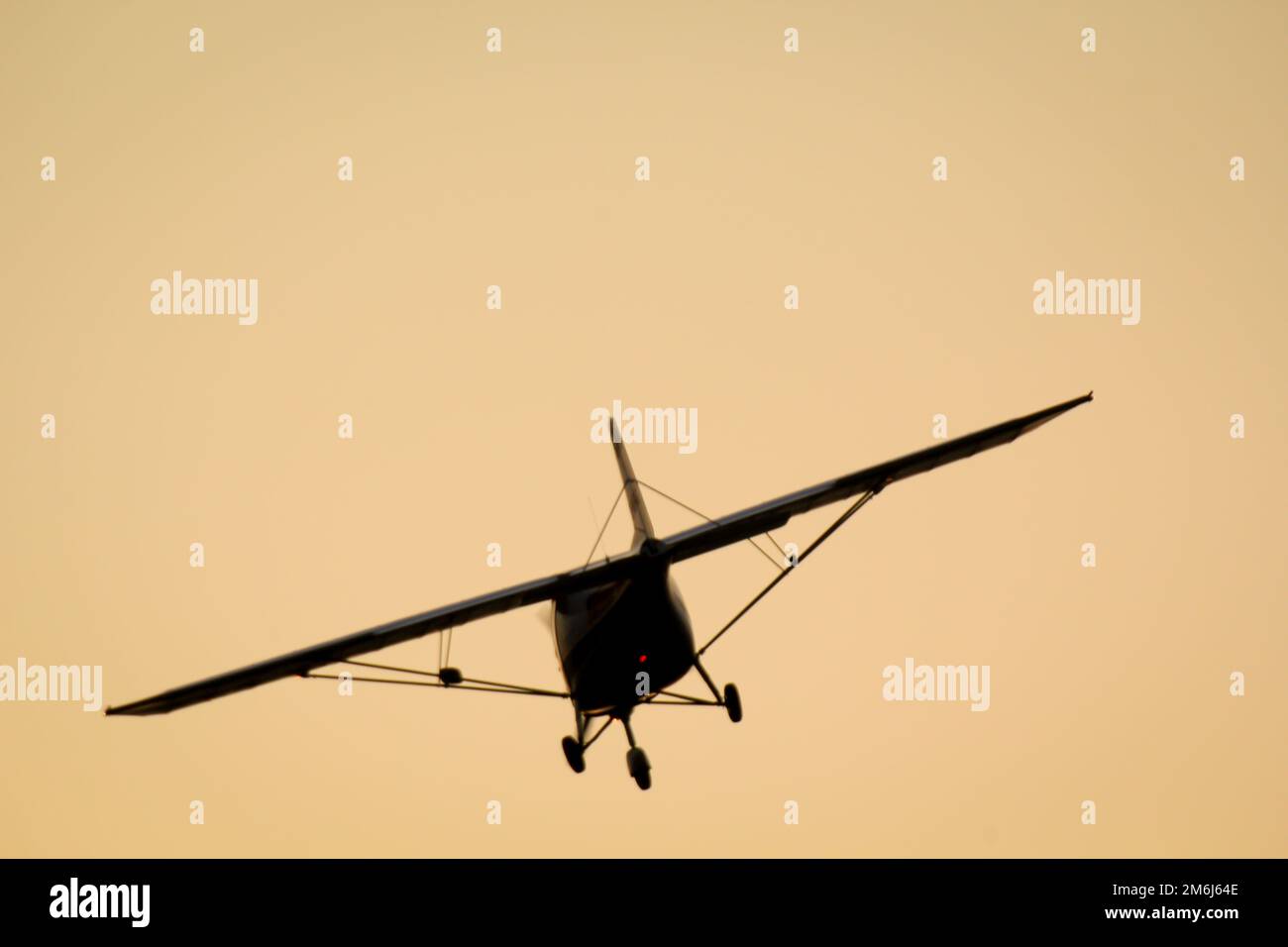 Un piccolo aereo vola verso il tramonto. Foto Stock