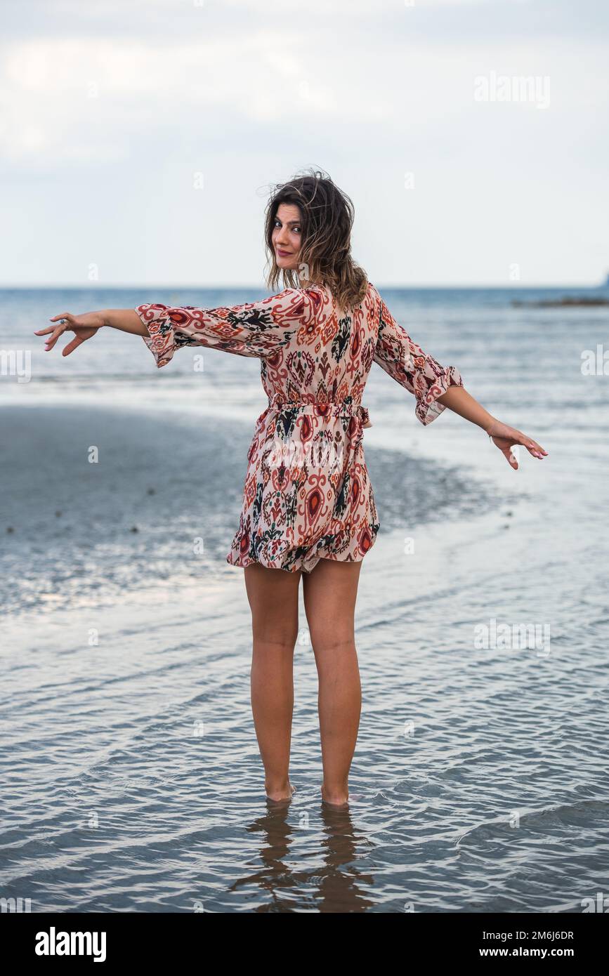 Donna che cammina in libertà mani aperte in spiaggia. Godersi le vacanze estive sull'oceano Foto Stock